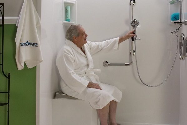 man sitting on a shower bench using the handheld shower wand