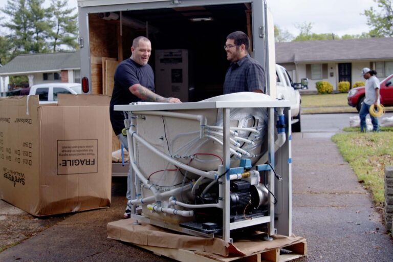 two men taking a walk-in tub off of the box truck