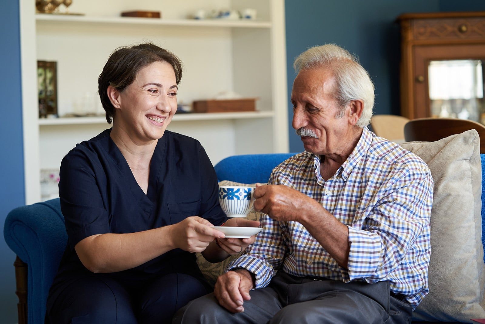 caregiver serving tee to an elderly man